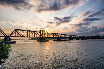Bridge over river against cloudy sky