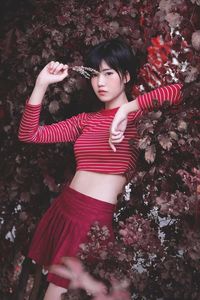 Portrait of young woman standing by plants