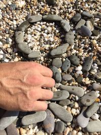 Cropped hand arranging pebbles at beach