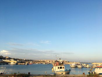 Boats moored at harbor against blue sky