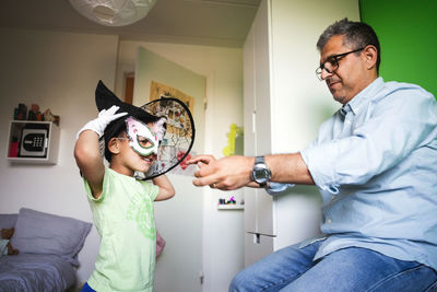 Father assisting son in wearing costume at home