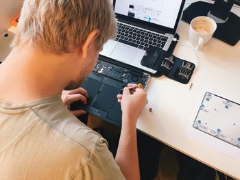 High angle view of man repairing computer part at table