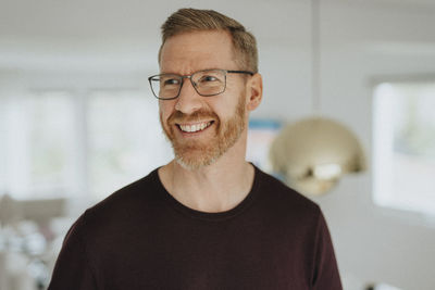 Smiling mature man wearing eyeglasses looking away at modern home