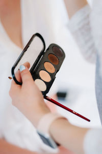 Cropped hand of woman holding make up box