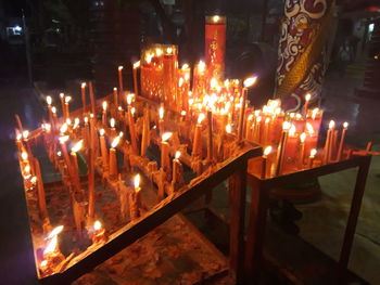 Illuminated candles in temple against building at night