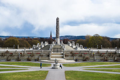 Tourists in park against cloudy sky