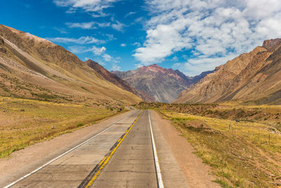 Road leading towards mountains against sky