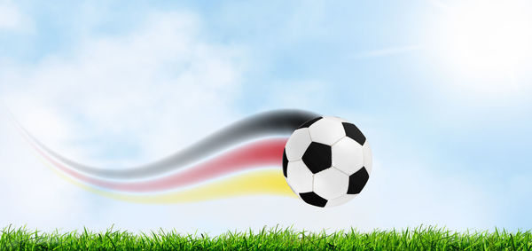 Close-up of soccer ball on field against sky