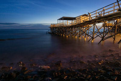 Pier over sea against sky at dusk