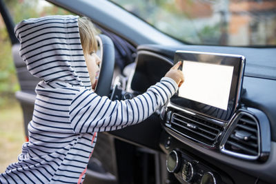 Curious toddler girl holding, touching, and turning a car mnultiedia touch screen player button