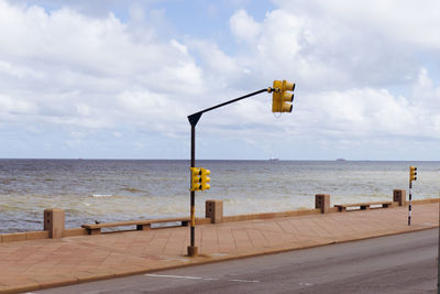 Street light by sea against sky