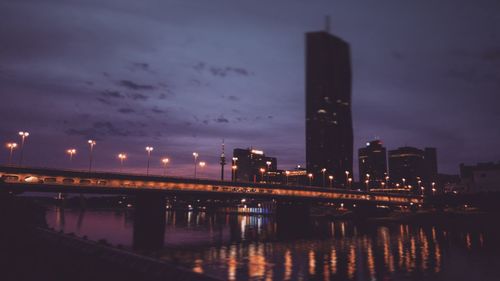 Illuminated bridge over river against sky at night