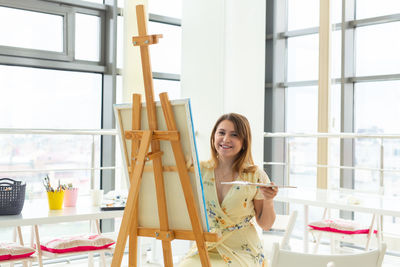 Portrait of smiling woman painting at home