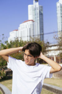 Mid adult woman standing by skyscrapers in city against sky