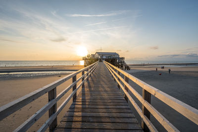 Pier over sea against sky during sunset