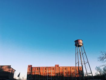 Low angle view of water tower against clear blue sky