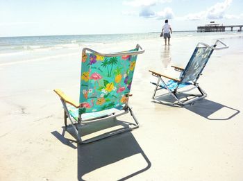 Man on chair at beach against sky