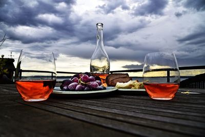 Close-up of drink and food on table against cloudy sky