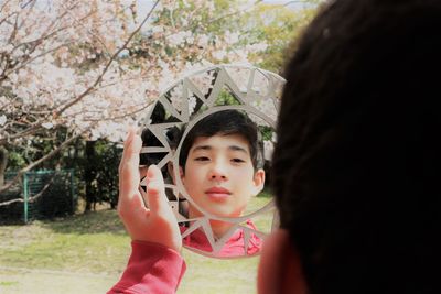 Close-up of boy looking in mirror at park