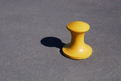 High angle view of yellow bollard with shadow on street