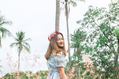 Happy young woman standing against trees