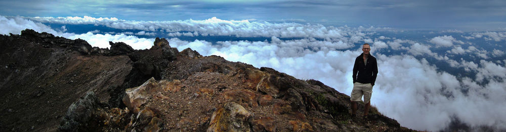 Panoramic view of man standing on mountain against sky