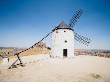 Traditional windmill on land against clear sky