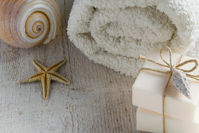 High angle view of soap bars with rolled up towel and starfish on wooden table
