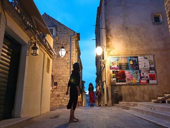 People walking on street amidst buildings in city