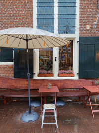 Empty chairs and tables at sidewalk cafe outside building