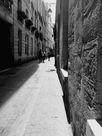 People walking on footpath amidst buildings in city