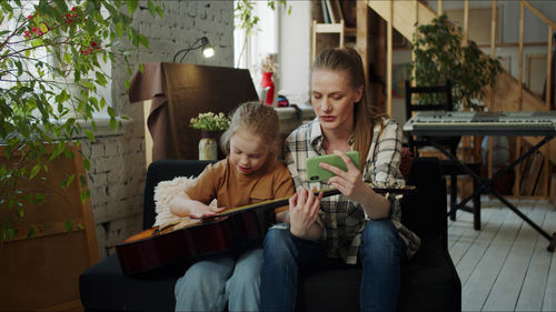 Mother teaching guitar to daughter