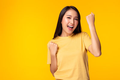 Portrait of a smiling young woman against yellow background