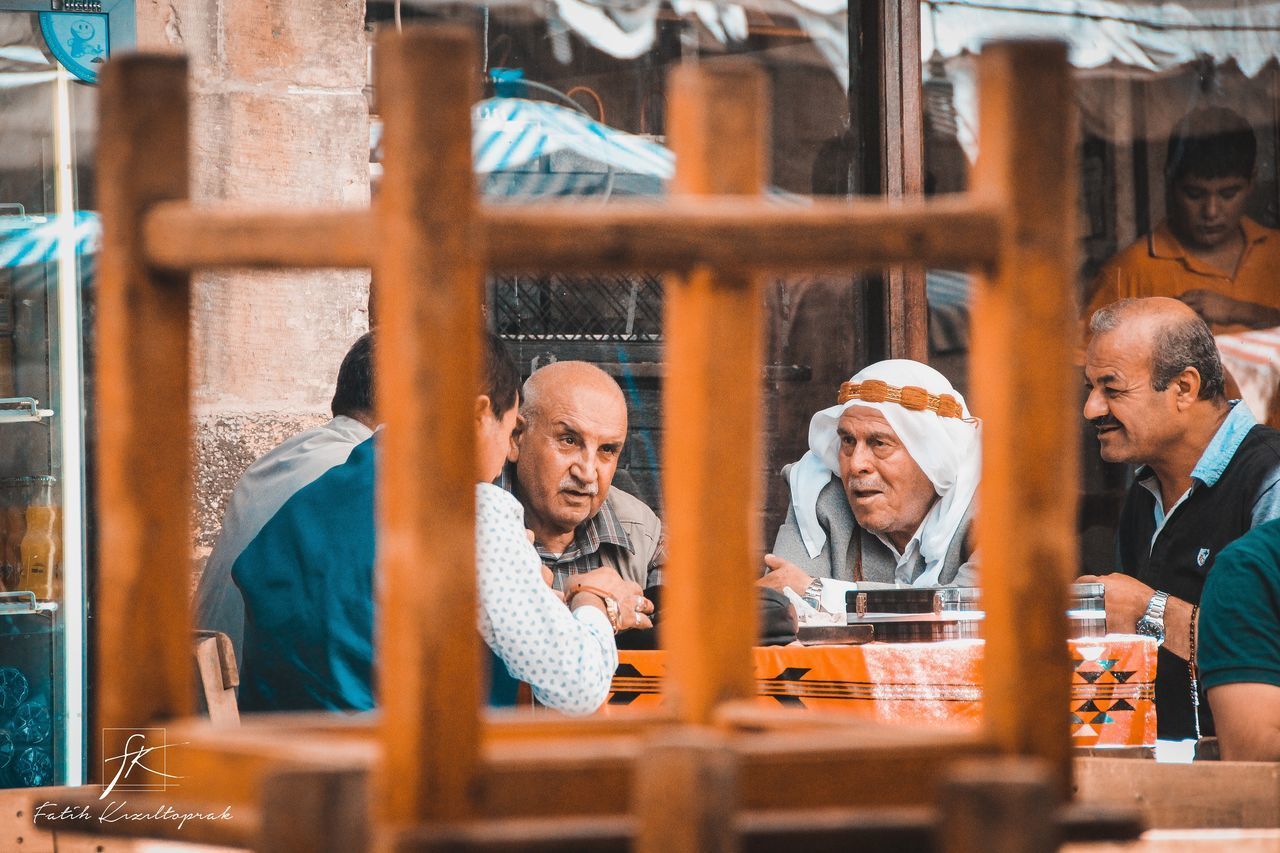 GROUP OF PEOPLE ON TABLE AGAINST WALL