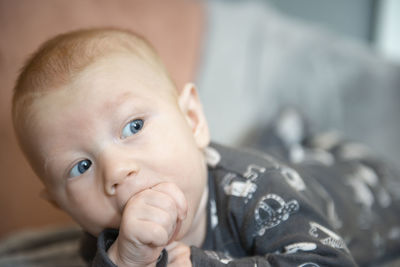 Close-up of adorable newborn baby boy sucking his hand or finger thumb