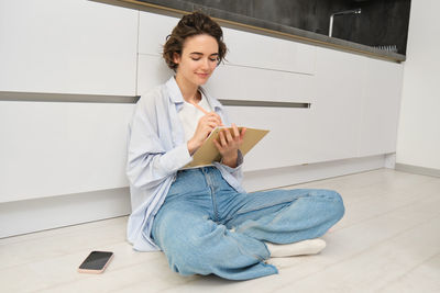 Portrait of young woman standing against wall