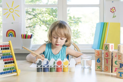 Funny beautiful happy child boy draws laughing with paint.