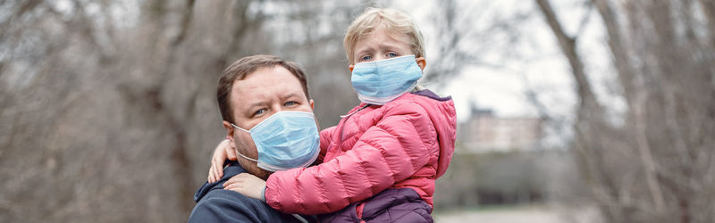 Father with child girl wearing sanitary face masks outdoor. banner header for website.