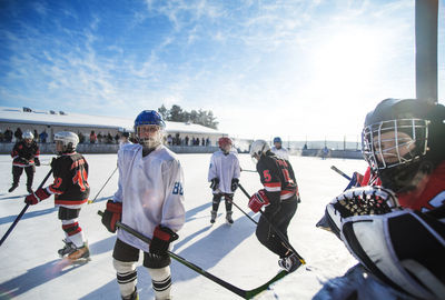 Players playing ice hockey on sunny day