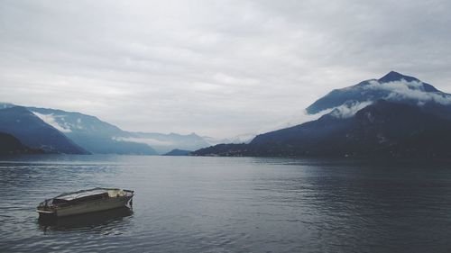 Lone boat in calm lake against mountain range