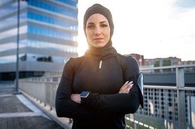 Portrait of woman standing against building in city