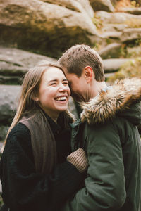 Smiling heterosexual couple standing against rock