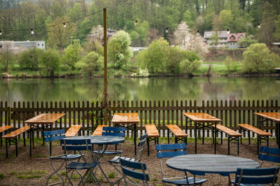 Chairs and tables in beer garden by river against trees