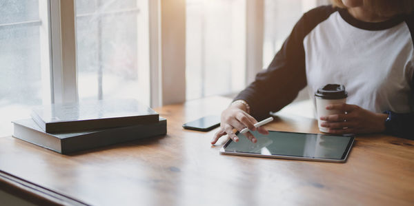 Midsection of man using smart phone on table