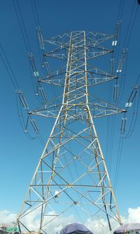 Low angle view of electricity pylon against blue sky