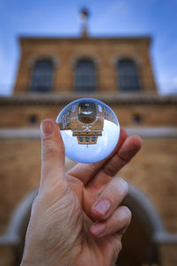 Close-up of human hand holding transparent sphere