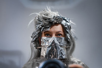 Portrait of woman wearing mask against white background at hair salon