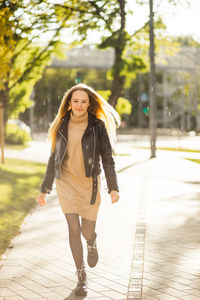 Portrait of young woman standing on footpath