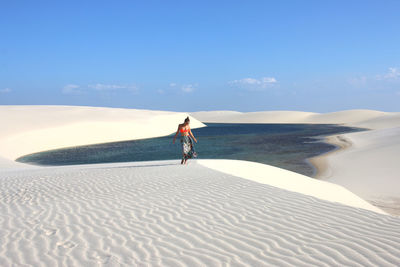 Happy young woman walking and dancing on a dune of lencois maranhenses, brazil