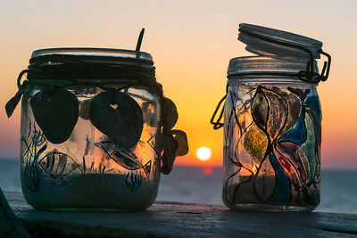 Close-up of glass jar on table against sky during sunset